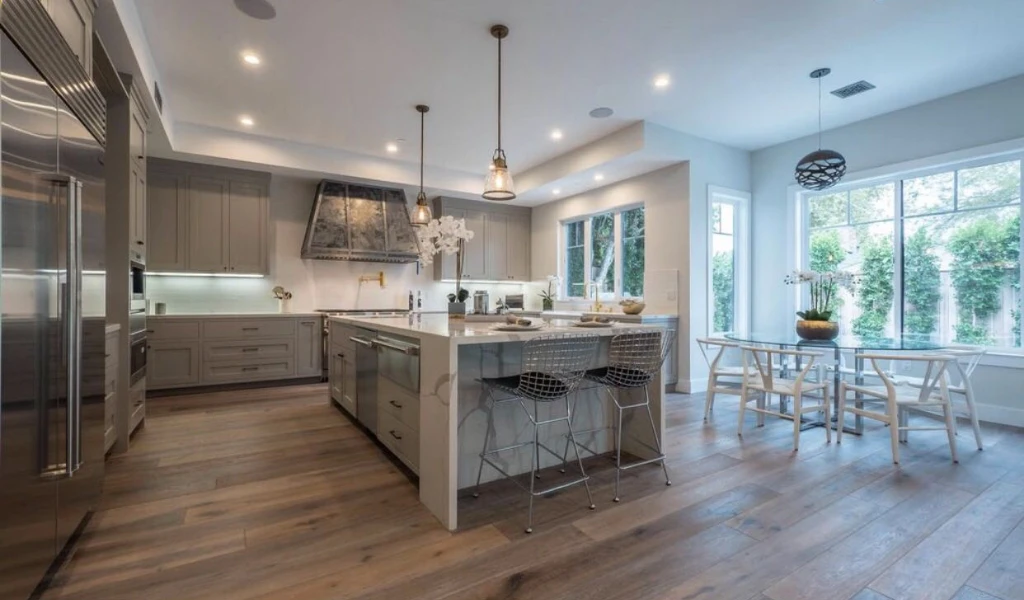 Modern kitchen and dining area with neutral color scheme, central island, pendant lighting, and hardwood floors.