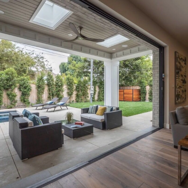 Modern living room seamlessly transitions to outdoor patio area with furniture and a pool.