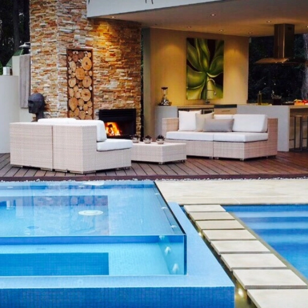 Modern outdoor living space with a swimming pool, fireplace, and lounge area.