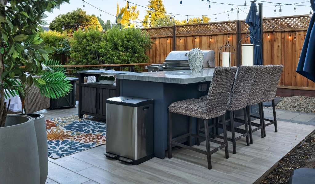 a relaxing and modern backyard living space and outdoor kitchen remodel with outdoor furniture and bar seating