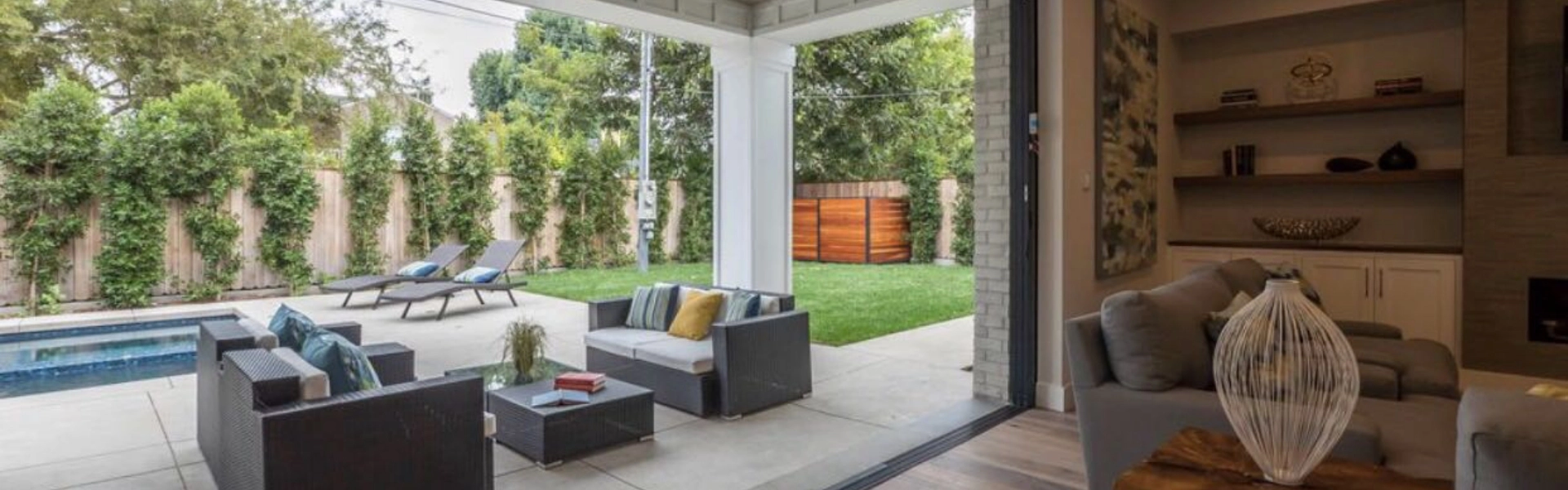 A luxury home addition that opens out to a beautiful backyard space, complete with a pool and seating areas.