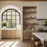 A minimal mid century designer organic modern kitchen interior with pine teak wood accents and brass fixtures finishes with a black arched window and green plant accents.