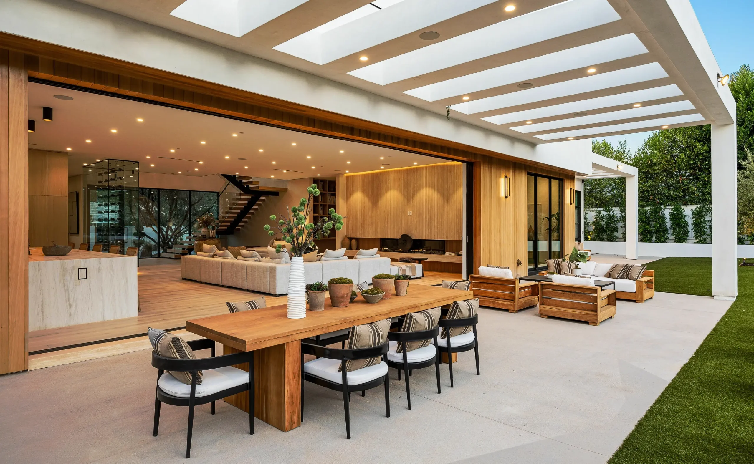A modern outdoor living space with wood features, cozy seating, and a wooden table.